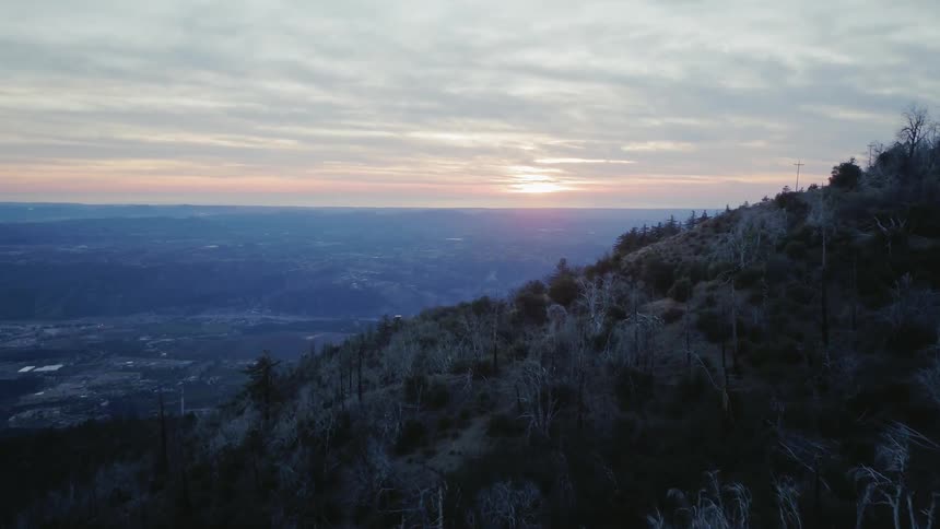 Hikers stand on a mountainside at sunset