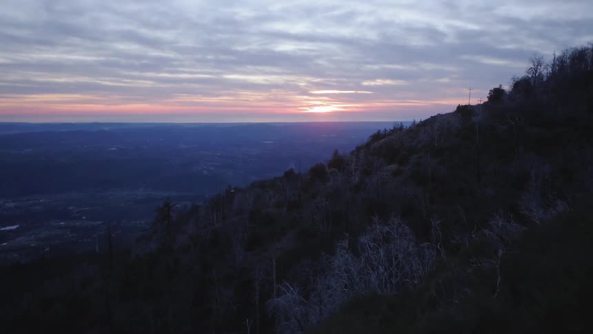 Two men take pictures standing on top of a hill at sunrise
