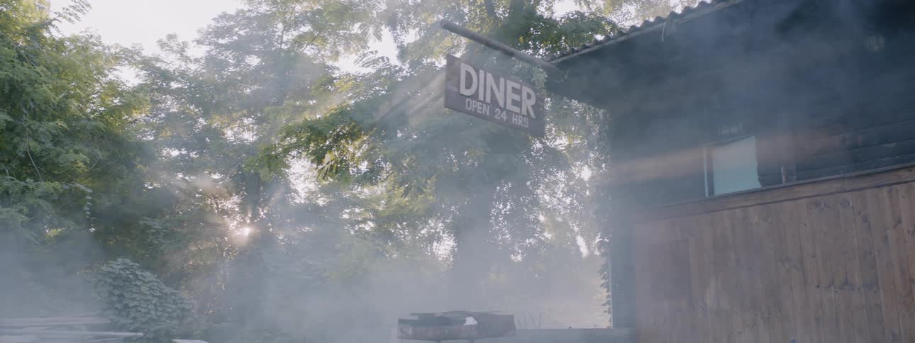 Sunlight is casting rays in fog as it drifts past a diner during the day