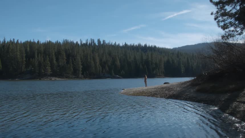 Hiker stands on a lakeshore