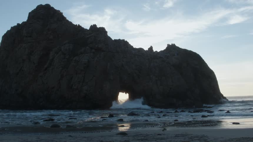 Waves crashing through a hole in a large rock
