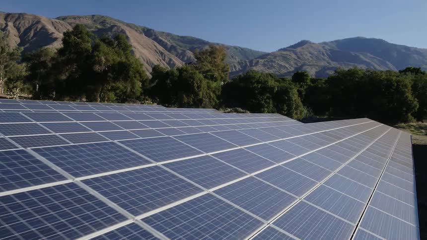 A solar farm is operating in an agricultural area during the day