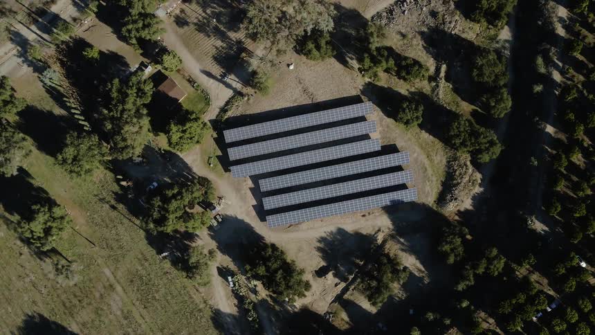 A solar farm is operating in an agricultural area during the day