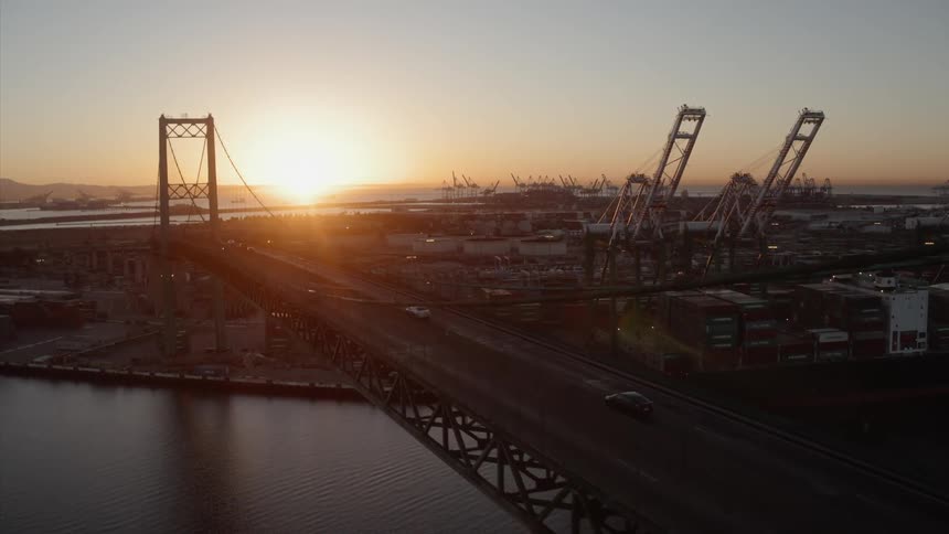 Cars drive over a city bridge at sunset