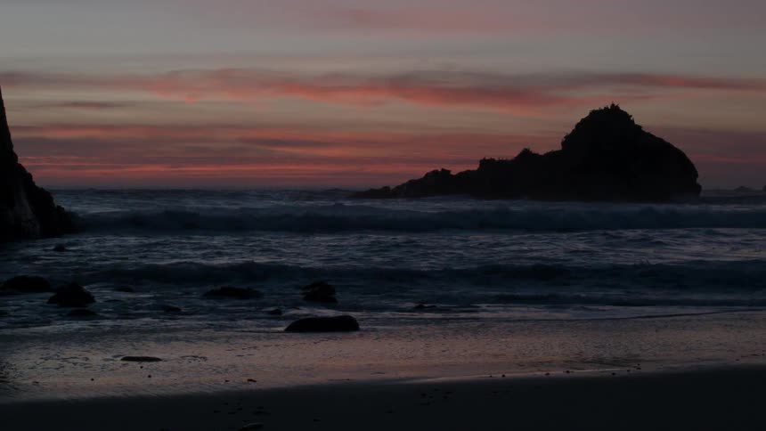 Waves splash up on the beach at sunset
