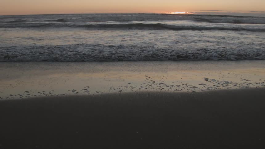 Waves rolling onto a beach at sunrise