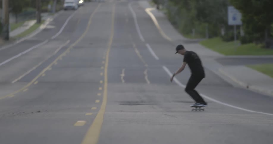 Man riding a skateboard down a hill of a street