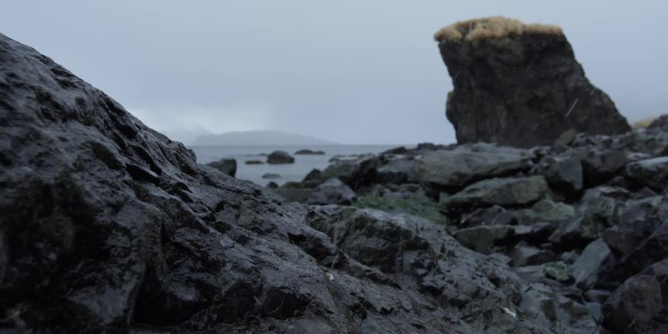 Snow falls on the rocky shore