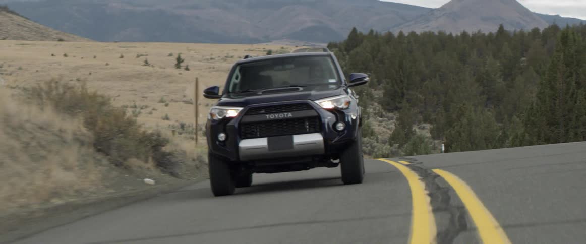 A vehicle travels up a hilly road