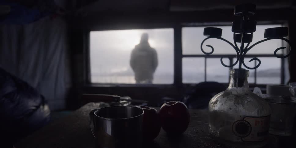 Man stands outside cabin in mountains on a cold day