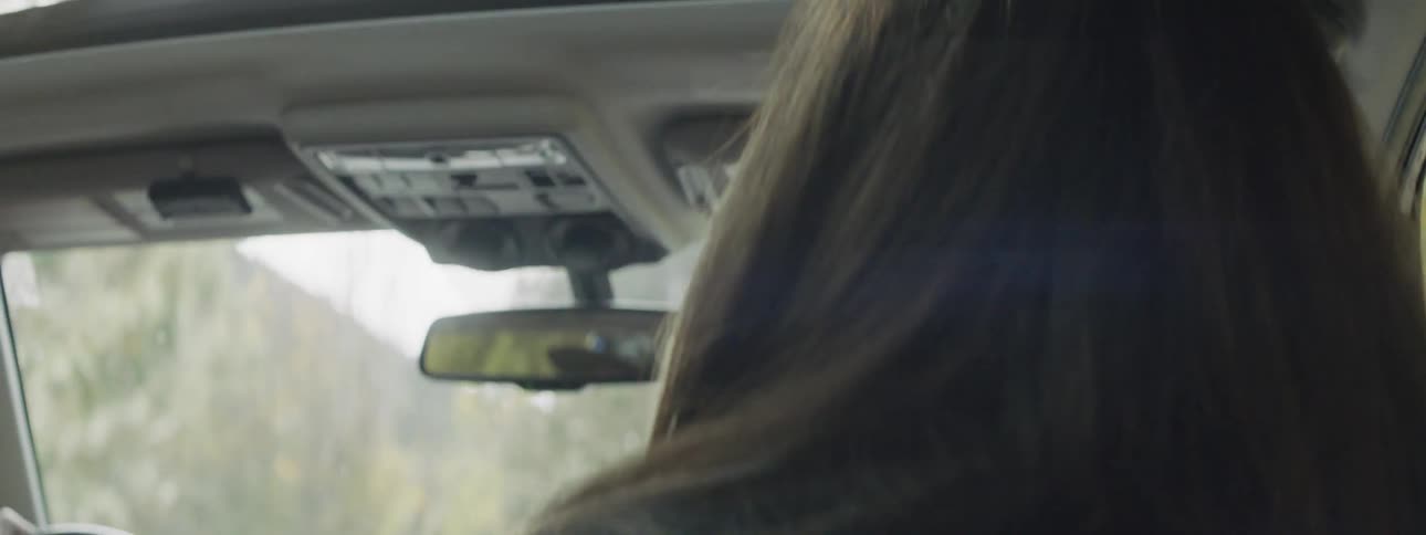 A woman rides in a car on a sunny day