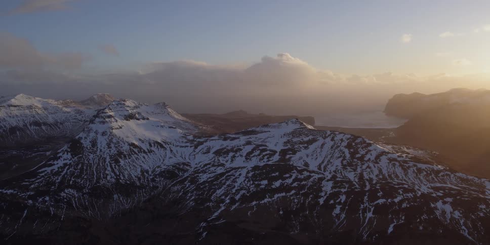 The sun is rising over a coastal mountain range in winter