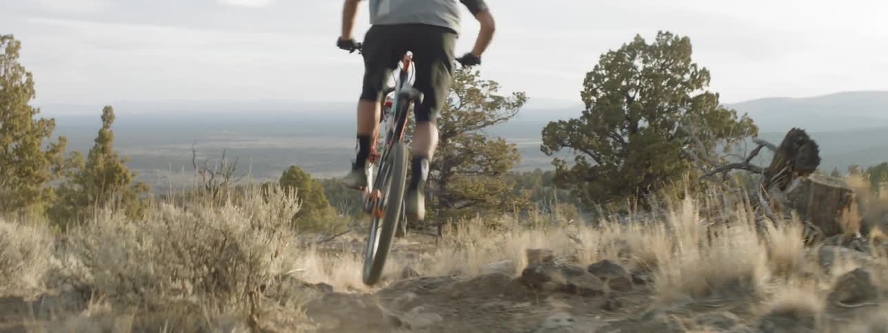 A man jumps and rides his mountain bike downhill