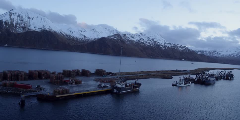 A long straight road goes down the middle of a lake with mountains in the background