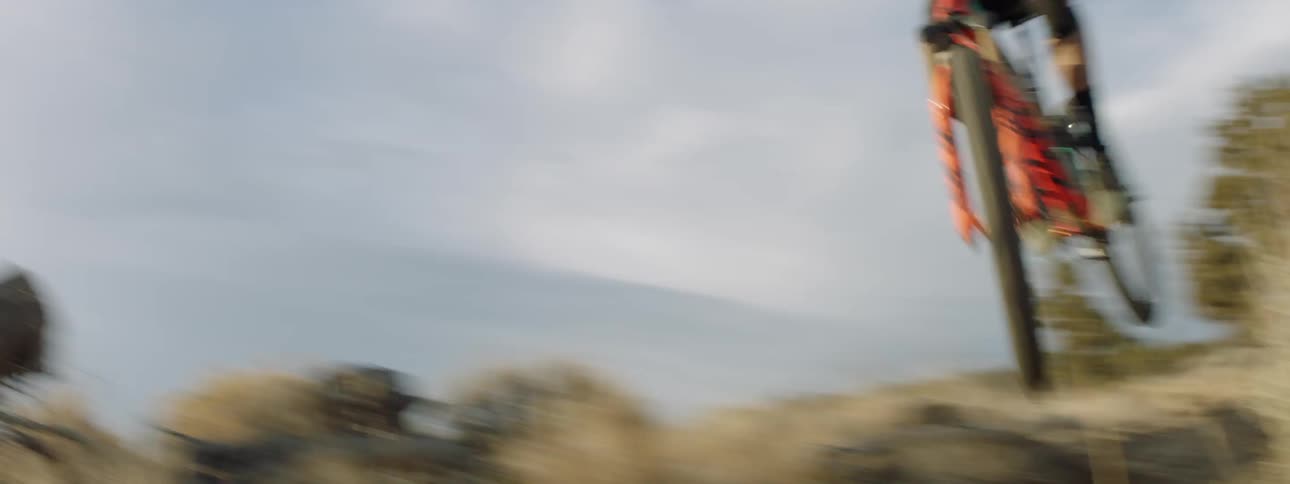 A bicyclist goes over a jump in mountains