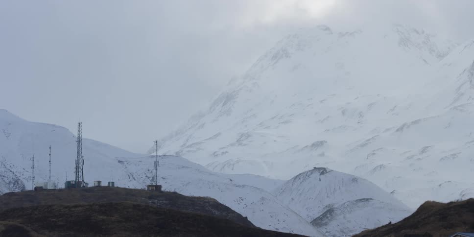 Clouds are drifting over communications towers in a mountain setting in winter