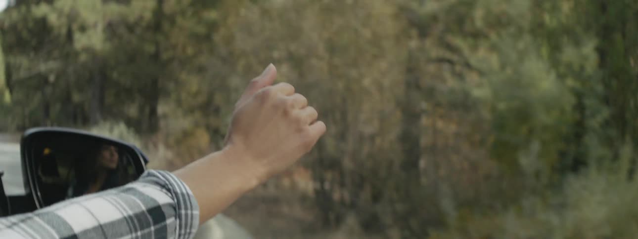 Person's hand waves outside of a traveling vehicle