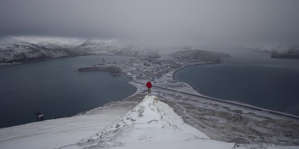 Person hikes in snow above ocean town