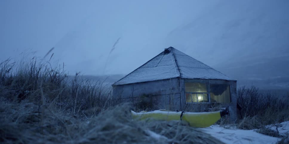 A person sits in a small shack out in the snow