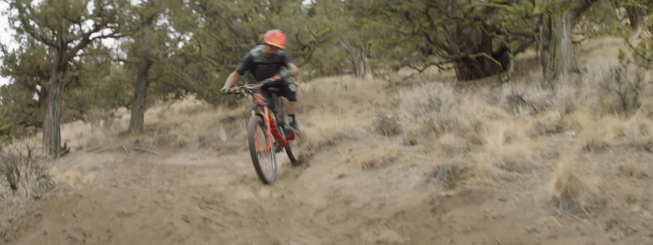 A man races his mountain bike down the dirt hill