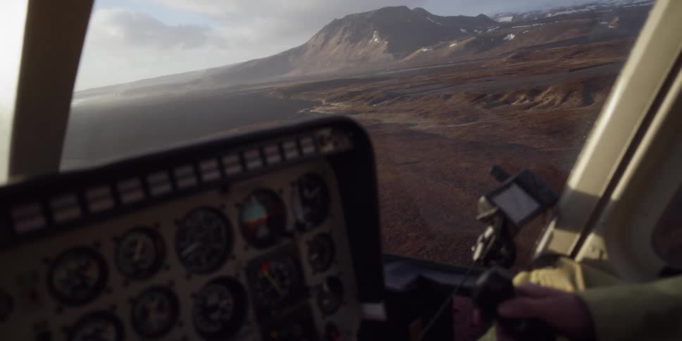 A pilot is flying a plane over a coastal tundra during the day