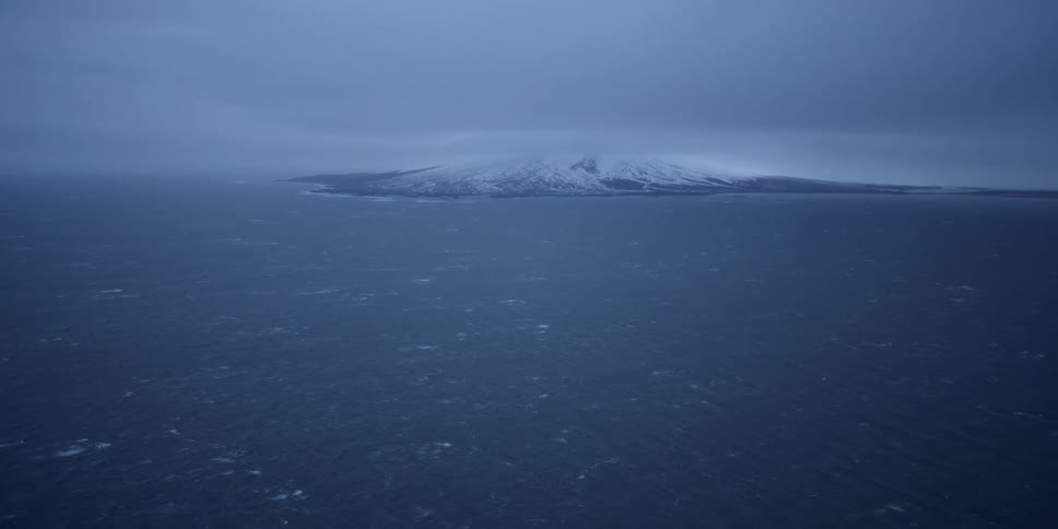 The island in the distance is surrounded by rough waters
