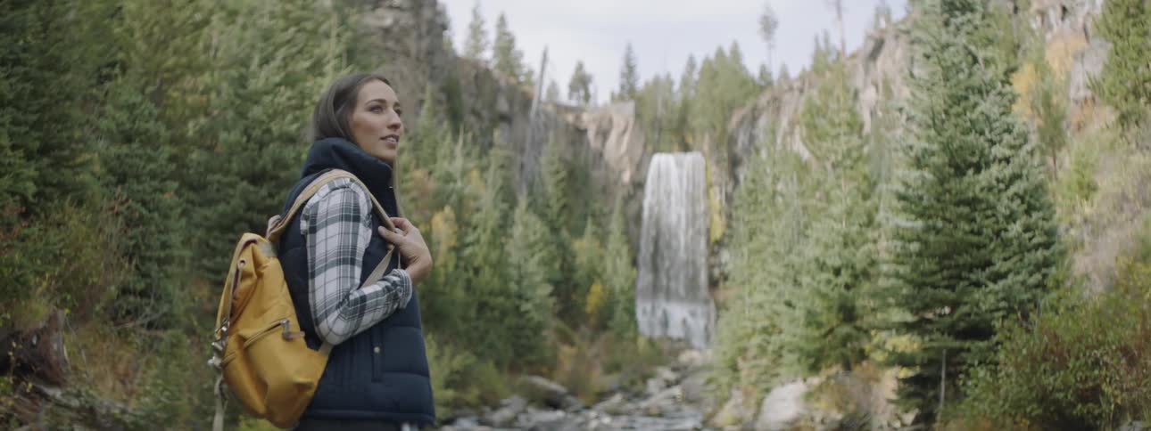 Woman wearing a backpack stands in the forest