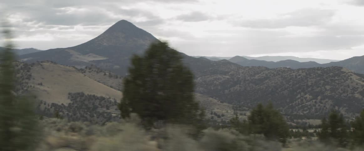 A vehicle drives in a rural area overlooking mountains