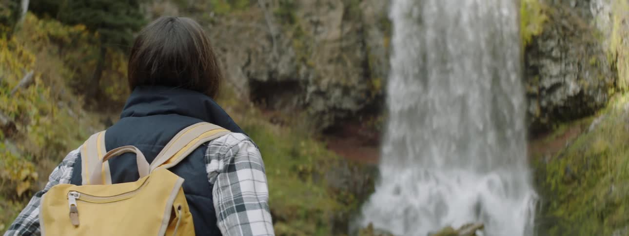 A woman is watching the water fall on the waterfall