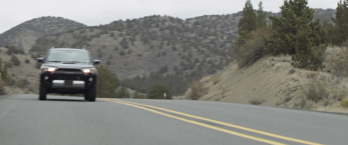 The vehicle races down the hillside road