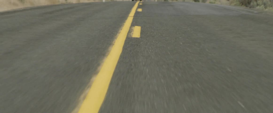 A truck drives down a road marked with yellow lines