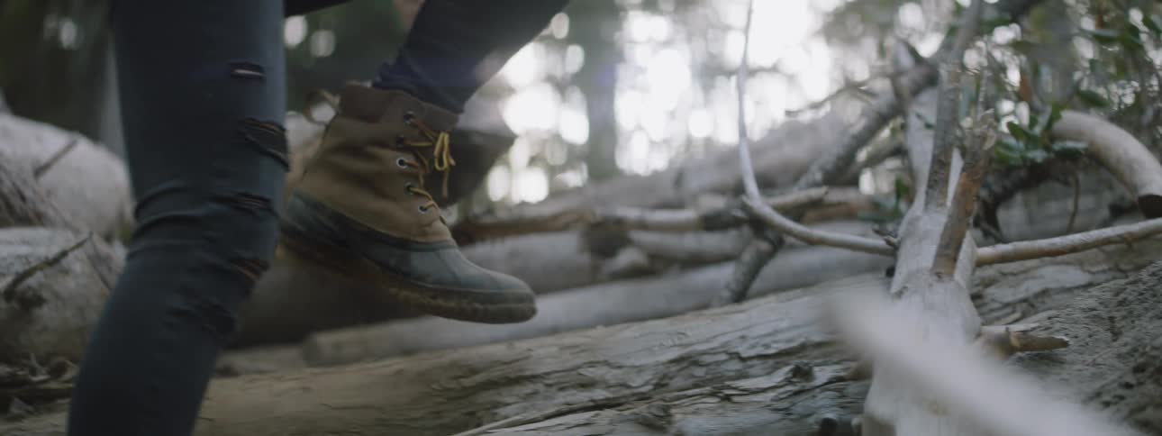 A woman hikes on fallen logs in the forest