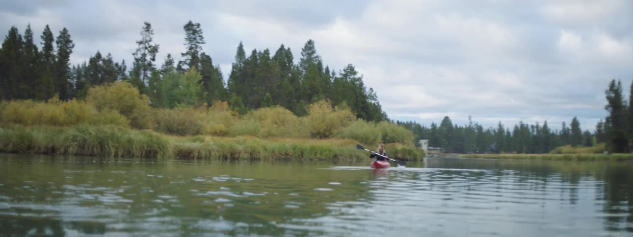 A woman kayaks on a forever river