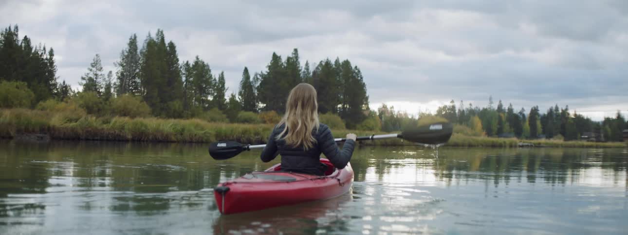 A woman is paddling a red kayak