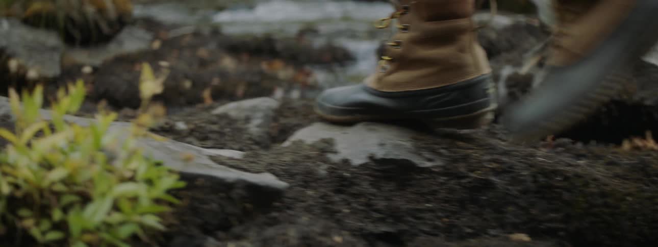 A hiker walks over dirt and rocks