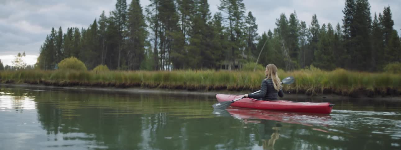 A woman is rowing a canoe in the water