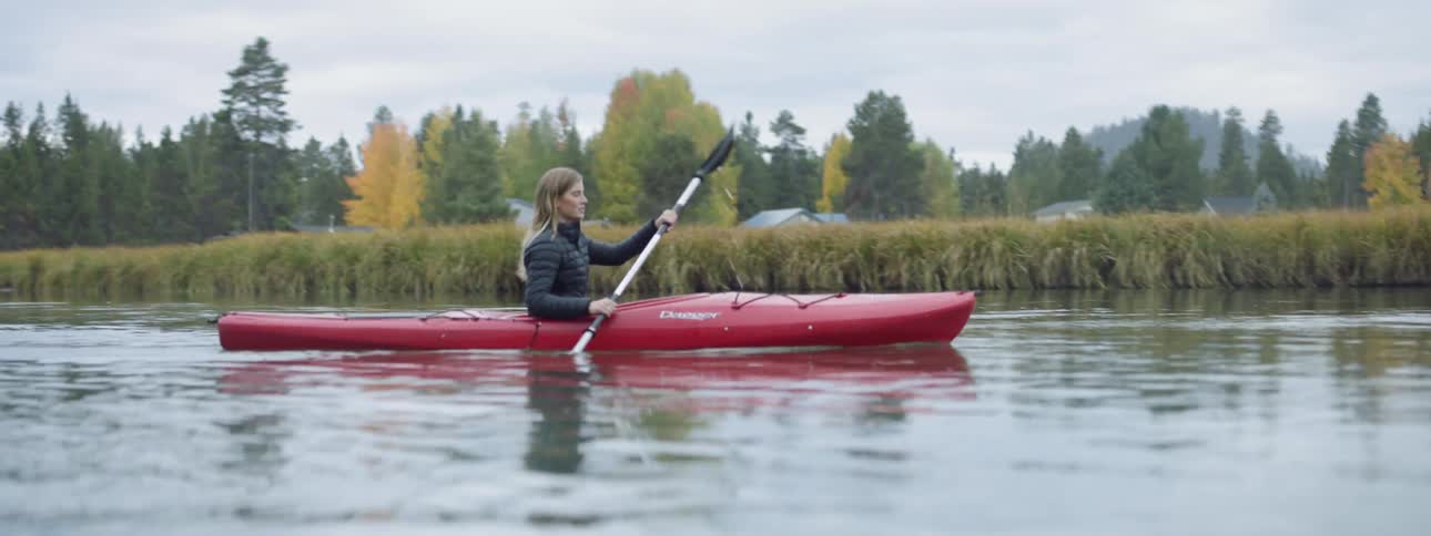 Woman paddles a kayak in a pond