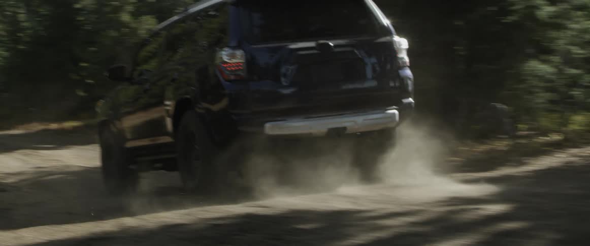 An suv drives down a bumpy dirt road on a sunny day