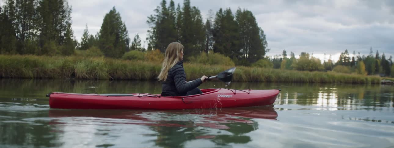 A woman is rowing a canoe on a cloudy day