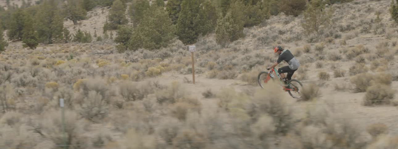 A man is riding a bike down a dirt track in the desert