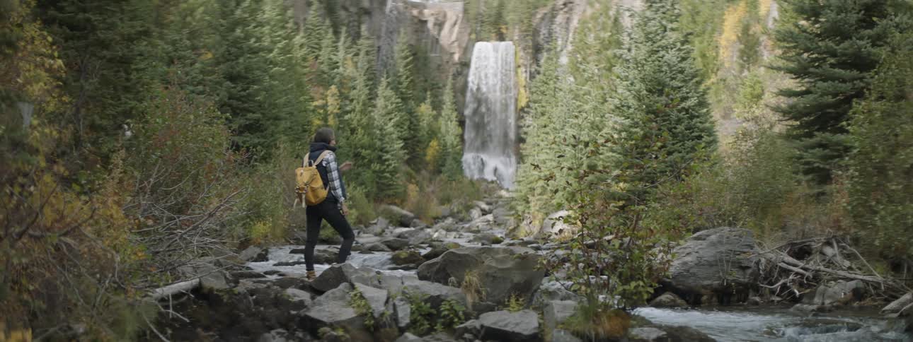 A person is watching a waterfall in the wilderness