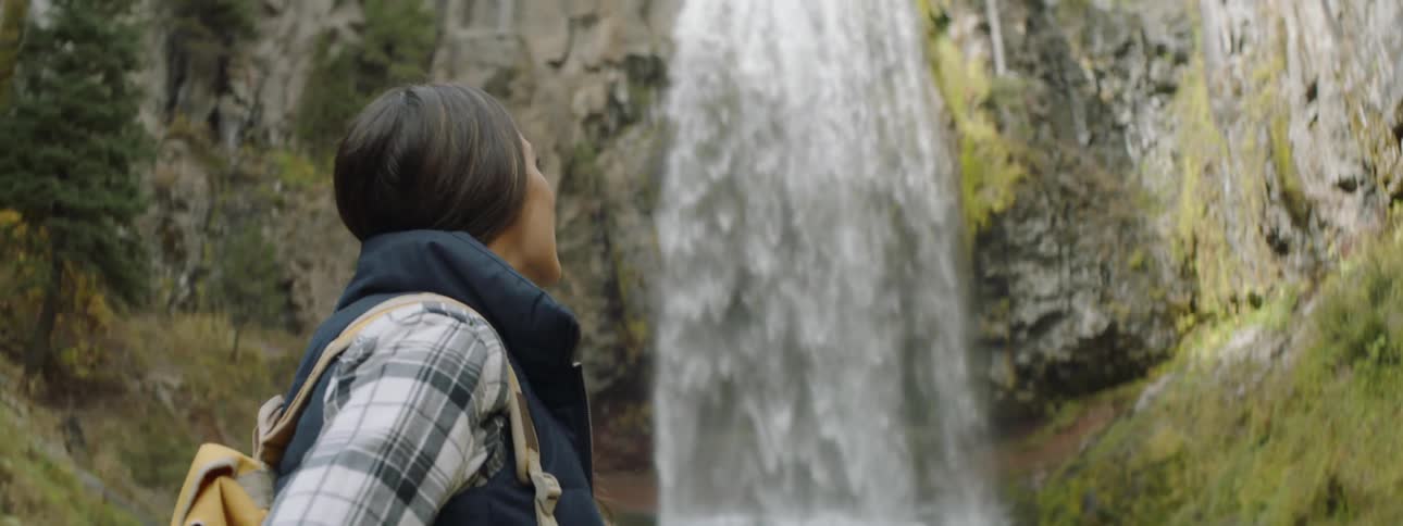 Hiker stands near a waterfall in the wilderness