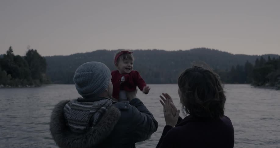 A family stands next to a mountain lake at sunset