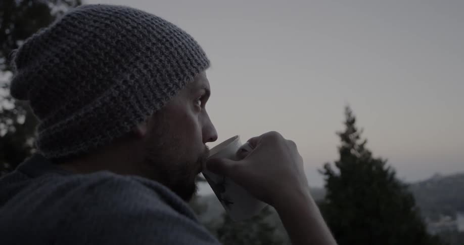 Man drinks coffee in the mountains at sunrise