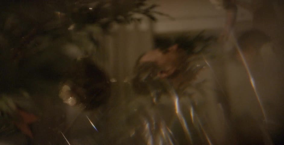 A man is playing with a toddler as they stand near a christmas tree