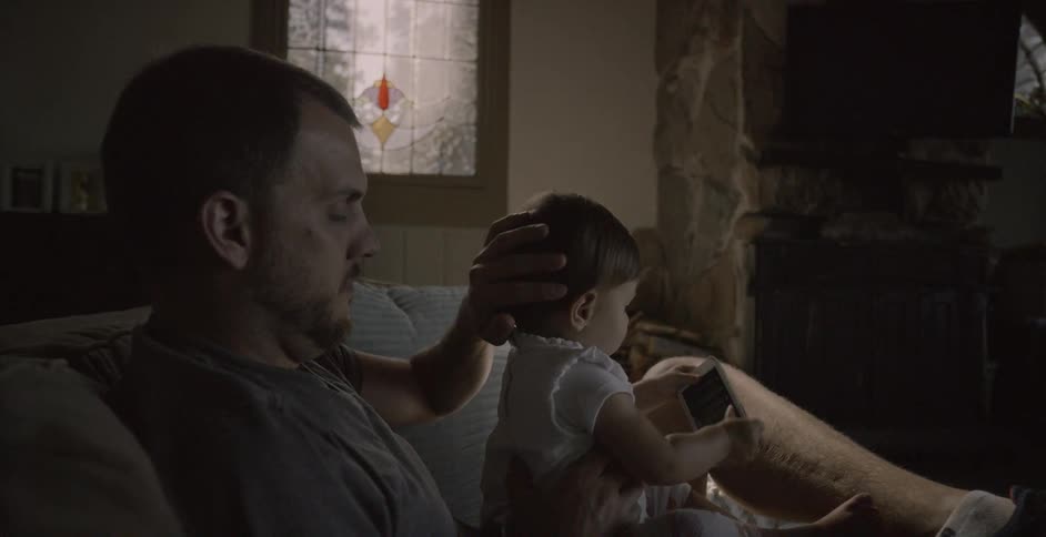 Man sits on a couch with a child on his lap