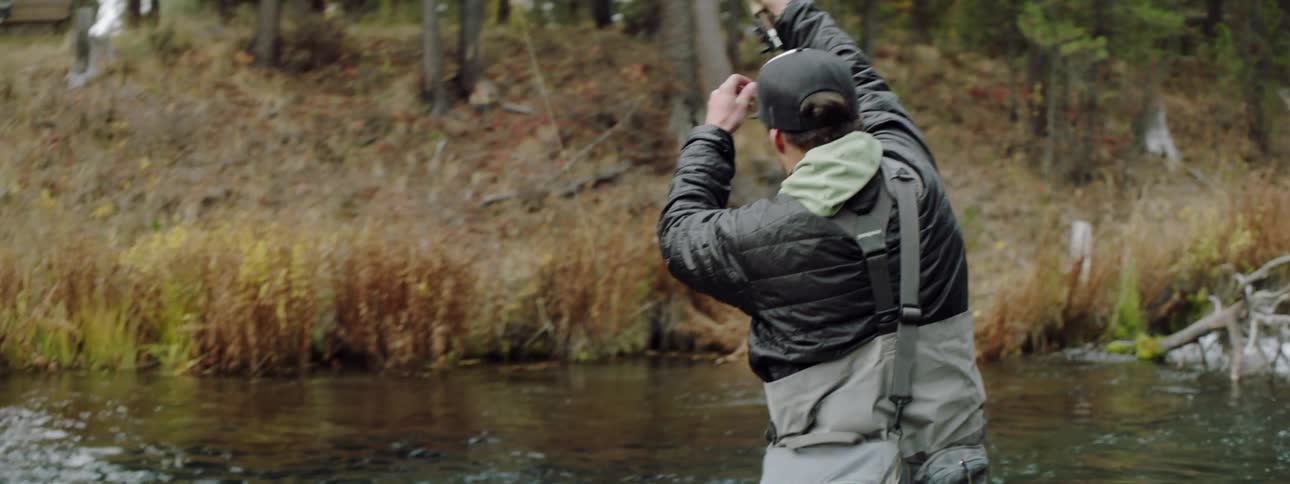 A man holds up his fishing pole and adjusts the line