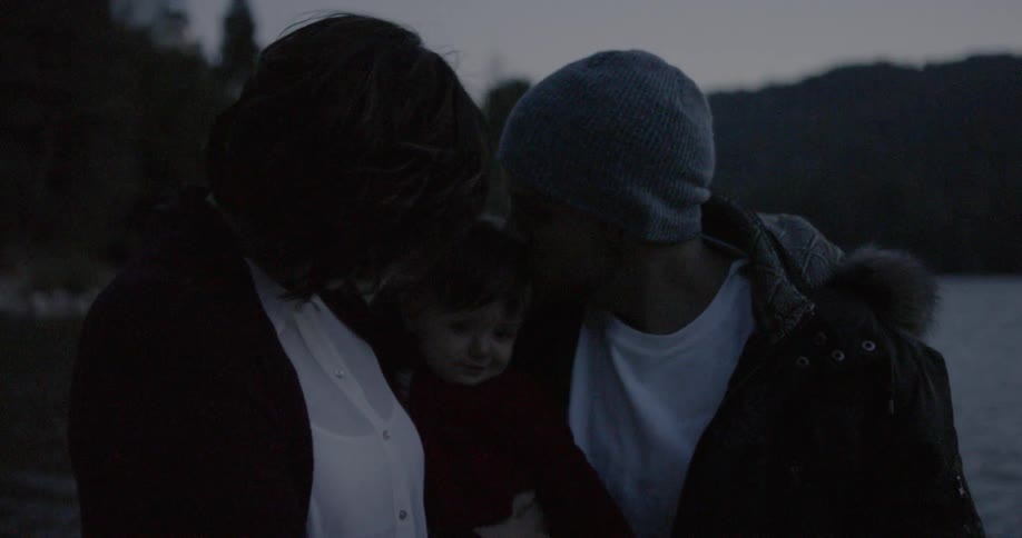 Man woman and child walk outside in the evening near a body of water