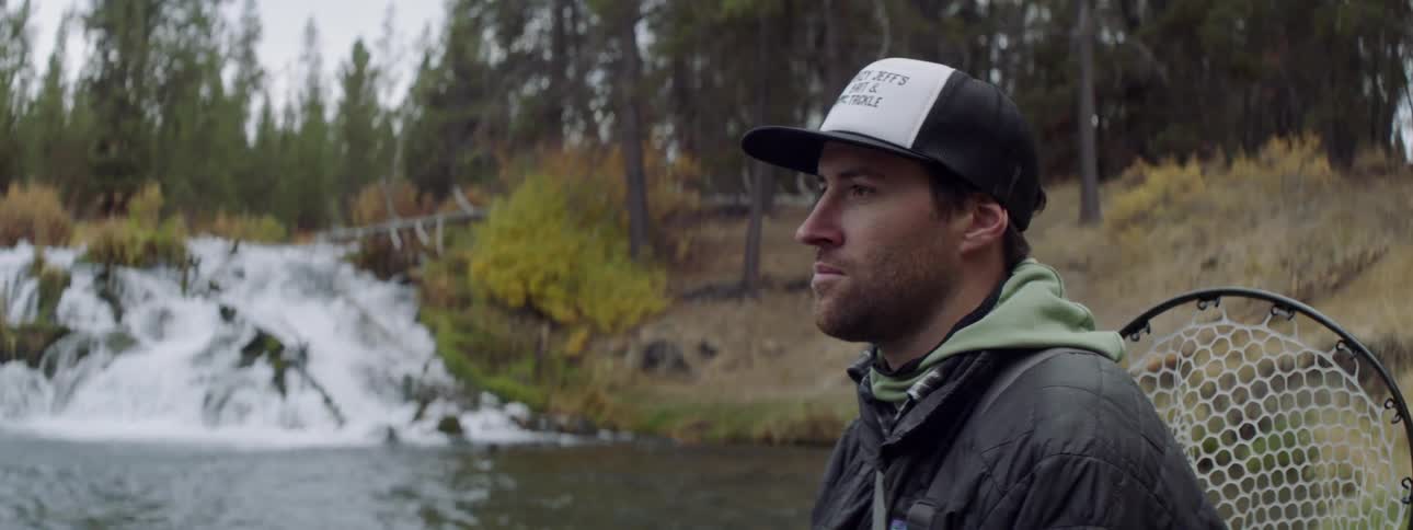 A man is fishing near the stream
