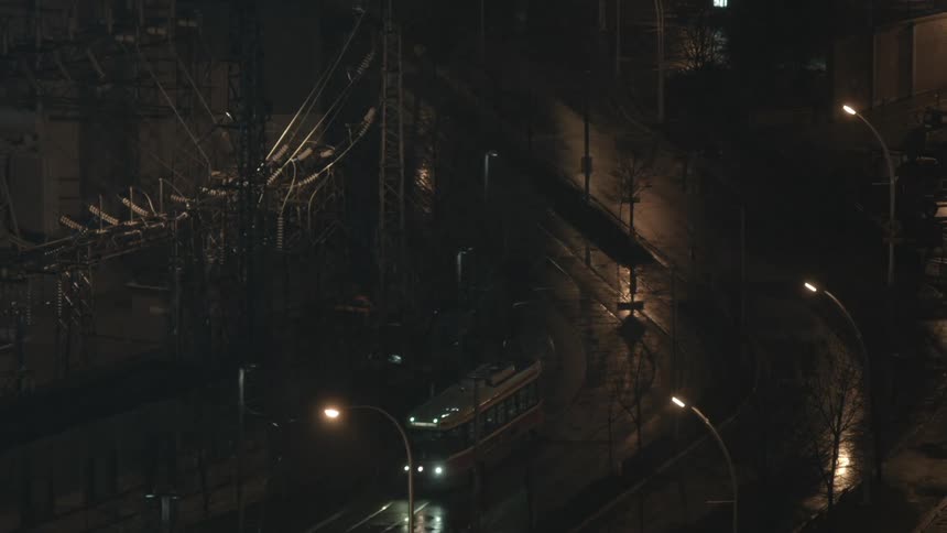 Streetcars drive along tracks in a city at night